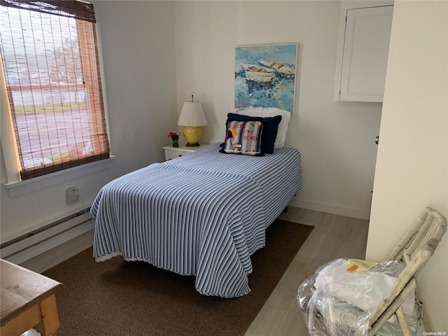 bedroom with hardwood / wood-style floors and a baseboard radiator