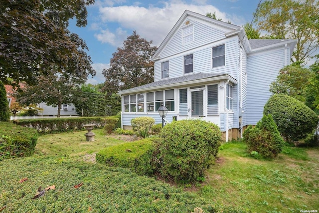 view of front of house with a sunroom and a front lawn