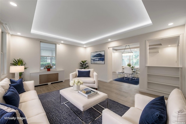 living room featuring radiator heating unit, hardwood / wood-style flooring, and a tray ceiling