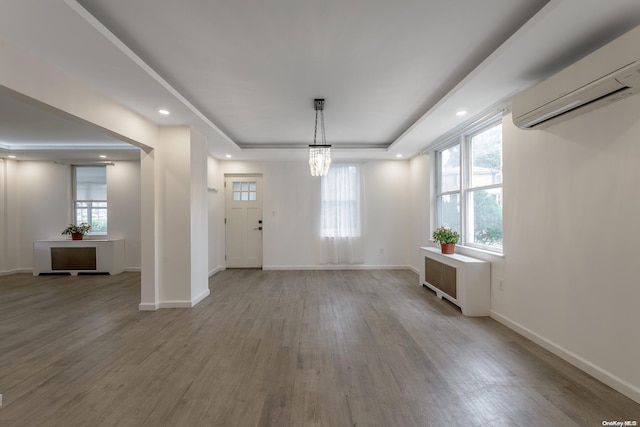 entrance foyer featuring a wall mounted AC, a wealth of natural light, a chandelier, and hardwood / wood-style flooring