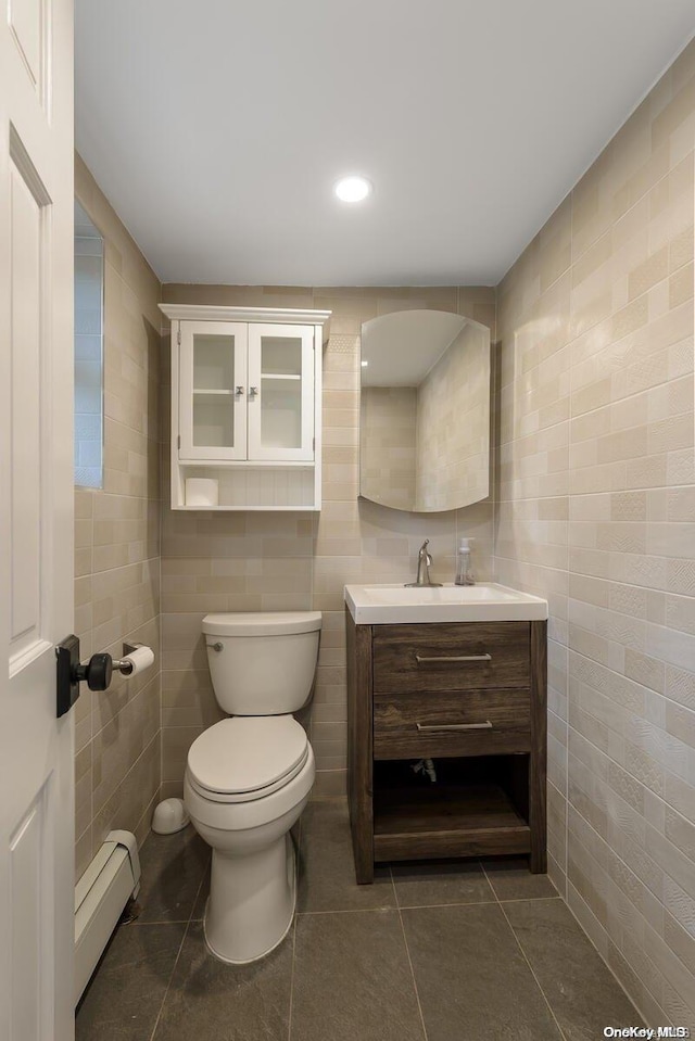 bathroom with tile patterned flooring, vanity, tile walls, and a baseboard radiator