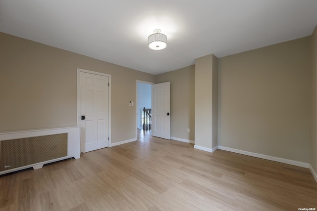 empty room featuring radiator and light hardwood / wood-style flooring