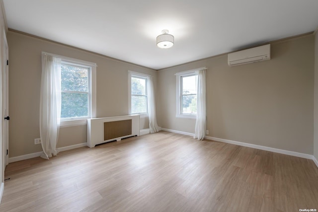 empty room featuring radiator, light hardwood / wood-style flooring, a wall mounted air conditioner, and ornamental molding