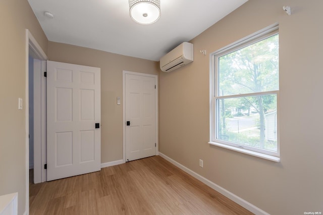 unfurnished bedroom with light wood-type flooring and a wall mounted AC