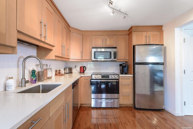 kitchen featuring sink, tasteful backsplash, light hardwood / wood-style flooring, light brown cabinetry, and appliances with stainless steel finishes