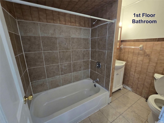 full bathroom with tiled shower / bath combo, tile patterned floors, toilet, vanity, and tile walls