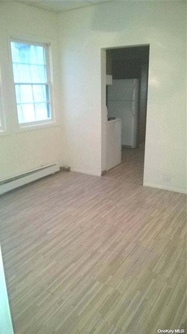 spare room with baseboard heating and light hardwood / wood-style floors