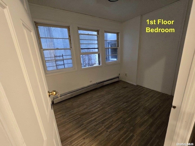 empty room featuring dark hardwood / wood-style floors and a baseboard radiator