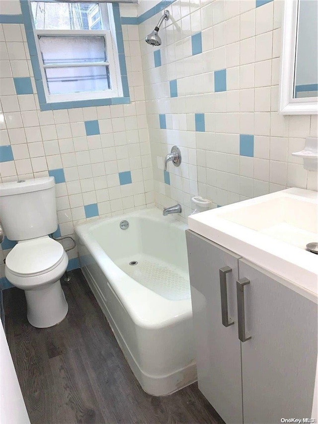 full bathroom with washtub / shower combination, toilet, wood-type flooring, and tile walls