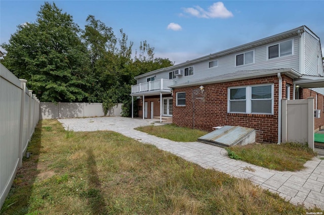 back of house with a yard and a balcony