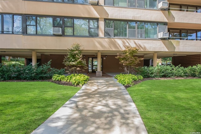 view of exterior entry featuring cooling unit and a lawn