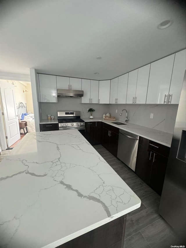 kitchen with light stone countertops, sink, white cabinetry, and stainless steel appliances