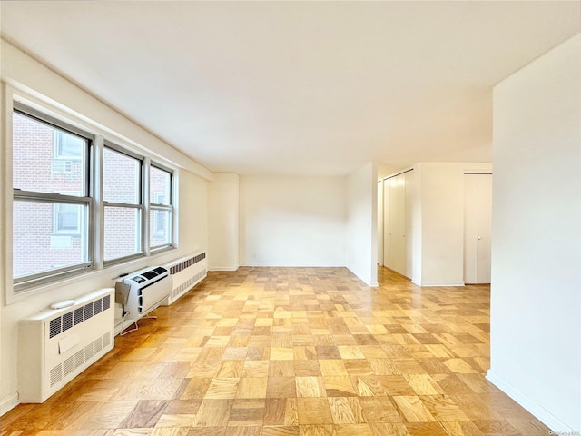 unfurnished room featuring radiator heating unit and light parquet flooring