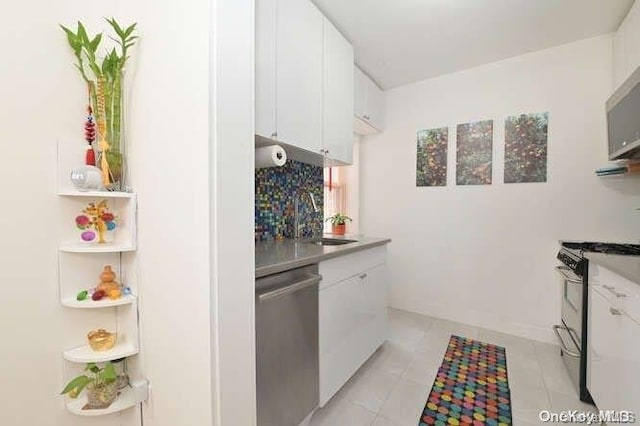 kitchen with white cabinetry, sink, stainless steel dishwasher, range with gas stovetop, and light tile patterned floors