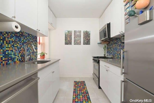 kitchen with tasteful backsplash, sink, white cabinets, and appliances with stainless steel finishes