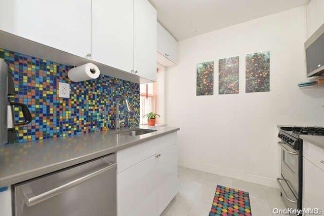 kitchen with white cabinetry, sink, light tile patterned flooring, and appliances with stainless steel finishes