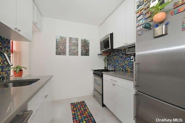 kitchen with white cabinetry, sink, tasteful backsplash, light tile patterned floors, and appliances with stainless steel finishes