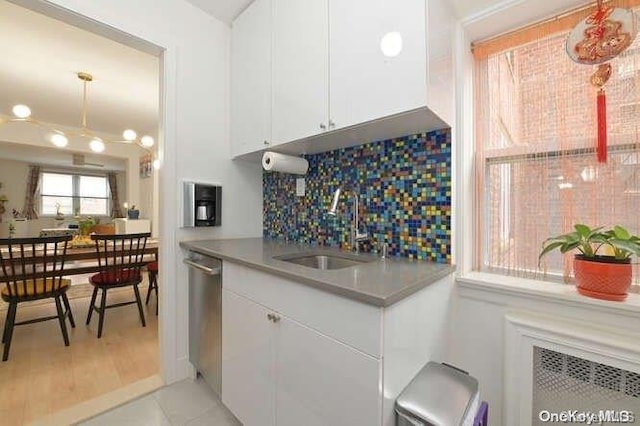 kitchen with dishwasher, sink, light wood-type flooring, tasteful backsplash, and white cabinetry