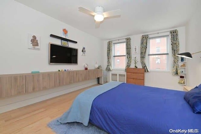 bedroom with hardwood / wood-style flooring, ceiling fan, and radiator