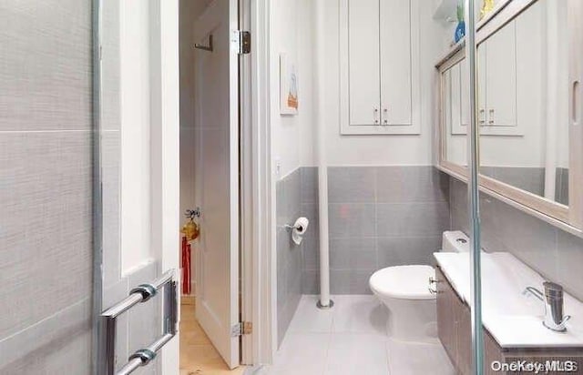 bathroom featuring tile patterned flooring, vanity, tile walls, and toilet