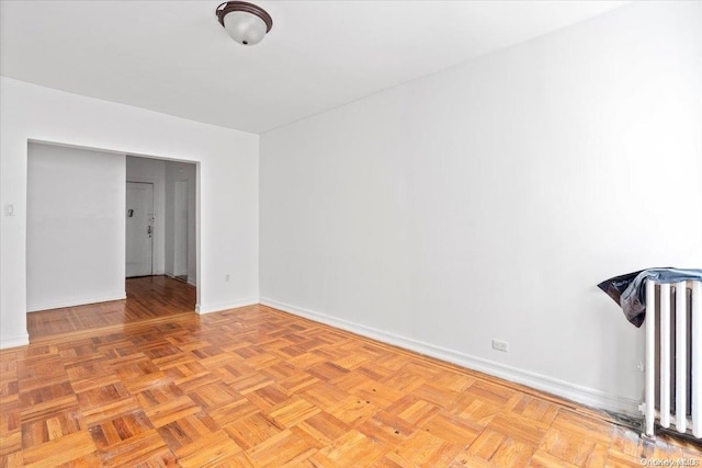 unfurnished room with radiator heating unit and light parquet floors