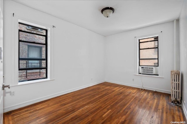 empty room with radiator heating unit, cooling unit, and dark wood-type flooring