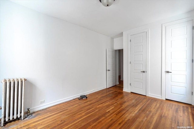 unfurnished bedroom with wood-type flooring and radiator