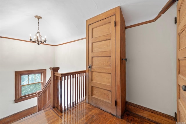 stairway featuring crown molding, hardwood / wood-style floors, and a notable chandelier