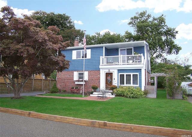 view of front of home with a patio area, a balcony, and a front yard