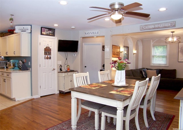 dining area with hardwood / wood-style floors and ceiling fan with notable chandelier