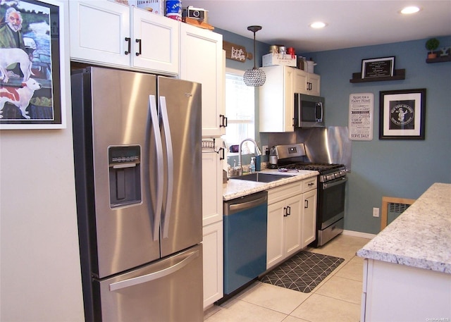 kitchen with stainless steel appliances, sink, light tile patterned floors, decorative light fixtures, and white cabinets