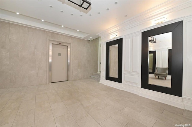 unfurnished room featuring ornamental molding and elevator