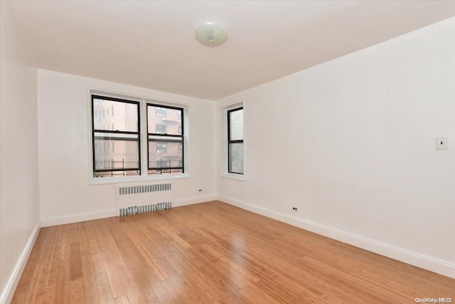 empty room with light hardwood / wood-style floors and radiator