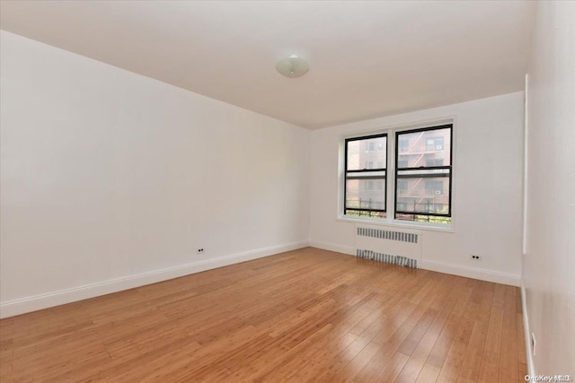 empty room featuring radiator heating unit and light hardwood / wood-style flooring