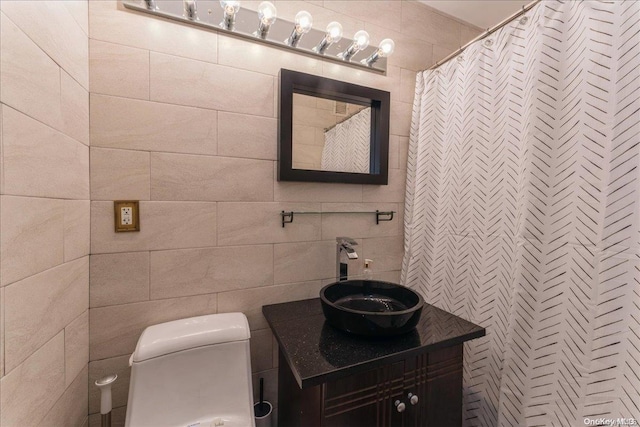 bathroom with vanity, tile walls, and toilet