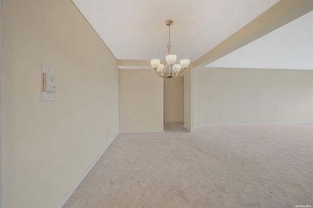 empty room featuring vaulted ceiling, light colored carpet, and a chandelier