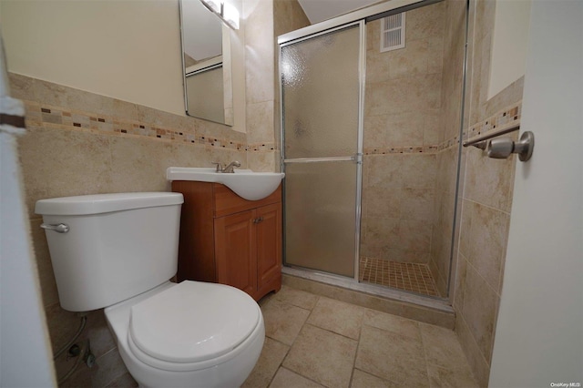 bathroom with vanity, toilet, tile walls, and a shower with shower door