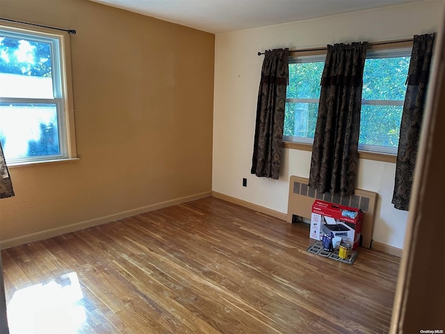 spare room featuring wood-type flooring and radiator heating unit