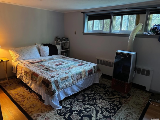 bedroom with radiator heating unit and wood-type flooring