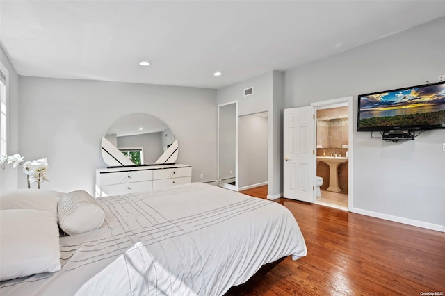 bedroom with ensuite bathroom and hardwood / wood-style flooring