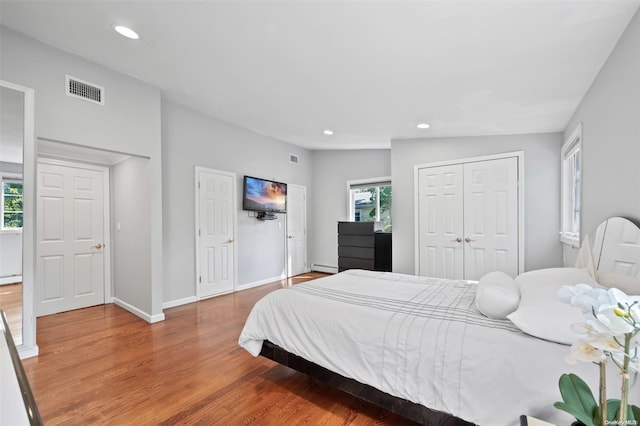 bedroom with hardwood / wood-style floors, a baseboard radiator, and vaulted ceiling