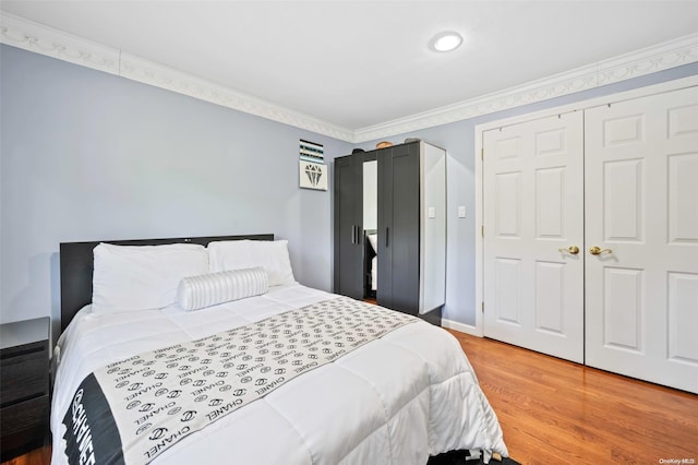 bedroom with hardwood / wood-style flooring, ornamental molding, and a closet