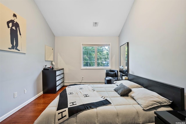 bedroom with dark hardwood / wood-style flooring, vaulted ceiling, and a baseboard heating unit