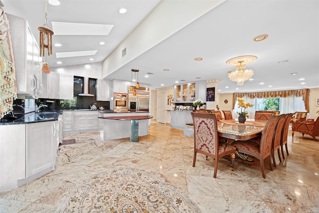 dining area featuring a skylight, an inviting chandelier, and sink