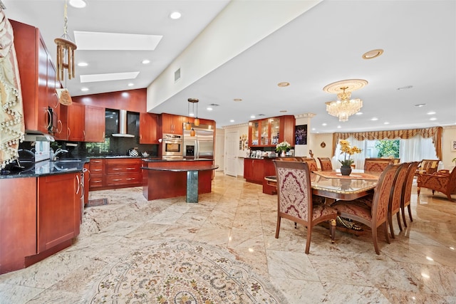 kitchen featuring a center island, wall chimney exhaust hood, stainless steel appliances, hanging light fixtures, and tasteful backsplash