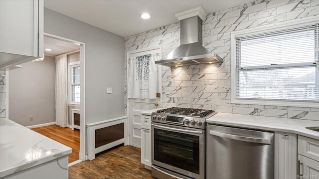 kitchen with light stone countertops, appliances with stainless steel finishes, dark hardwood / wood-style flooring, tasteful backsplash, and wall chimney range hood