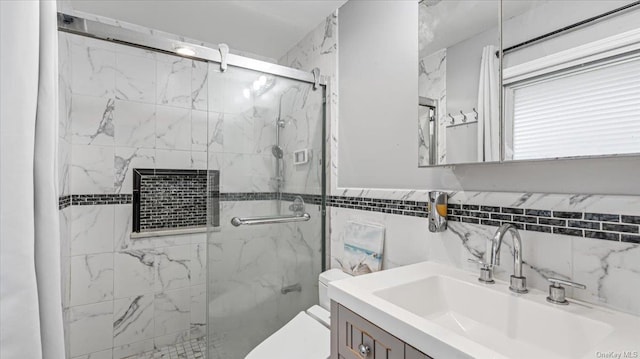 bathroom featuring vanity, toilet, tile walls, and a shower with shower door