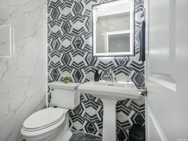 bathroom with toilet and tile walls