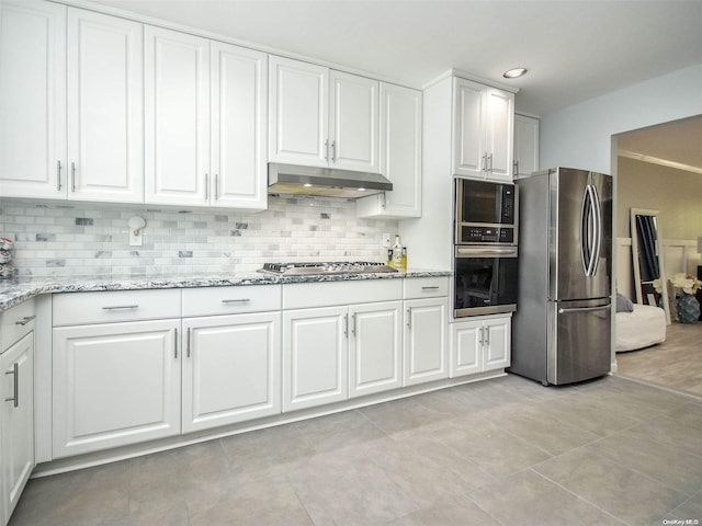 kitchen featuring appliances with stainless steel finishes, tasteful backsplash, light stone counters, light tile patterned floors, and white cabinets