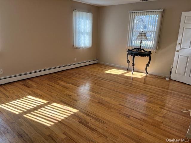 empty room with a baseboard radiator, baseboards, and wood finished floors